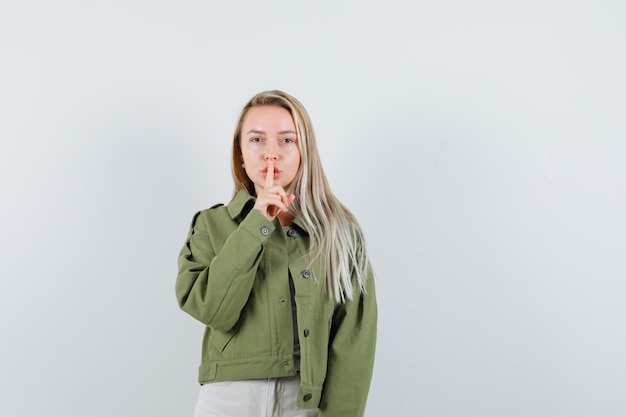 Free Photo young lady showing silence gesture in jacket, pants and looking confident. front view.