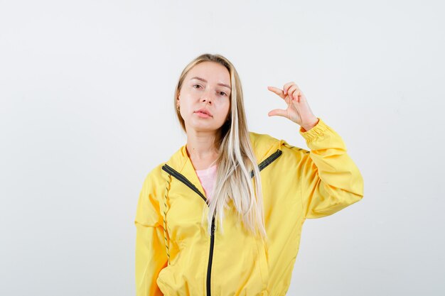 Young lady showing small size sign in t-shirt, jacket and looking confident