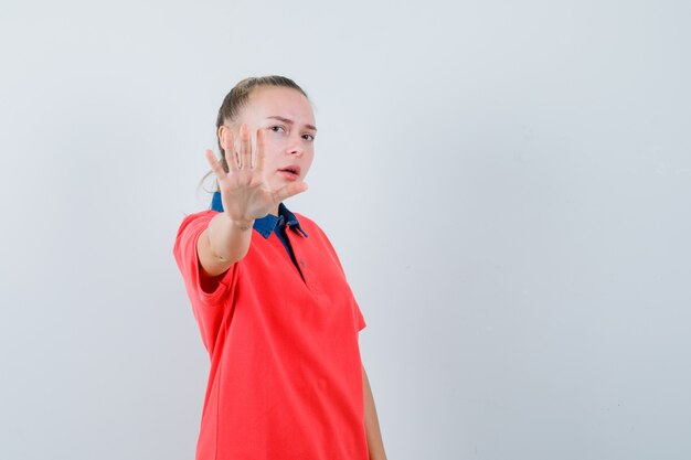 Young lady showing stop gesture in t-shirt and looking annoyed