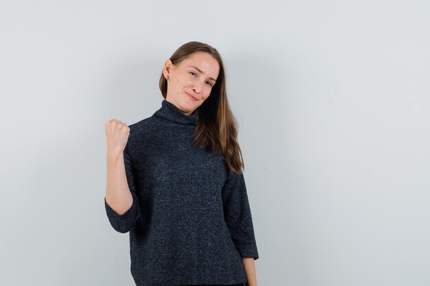 Young lady showing winner gesture in shirt and looking lucky