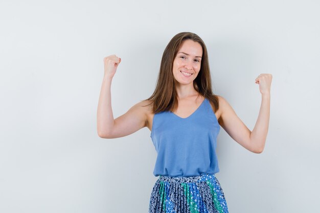 Young lady in singlet, skirt showing winner gesture and looking happy