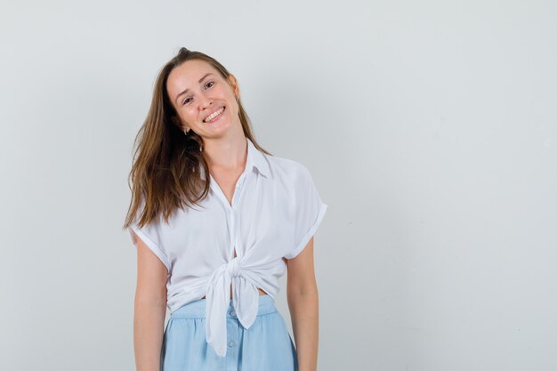 Young lady smiling while looking at front in blouse, skirt and looking positive