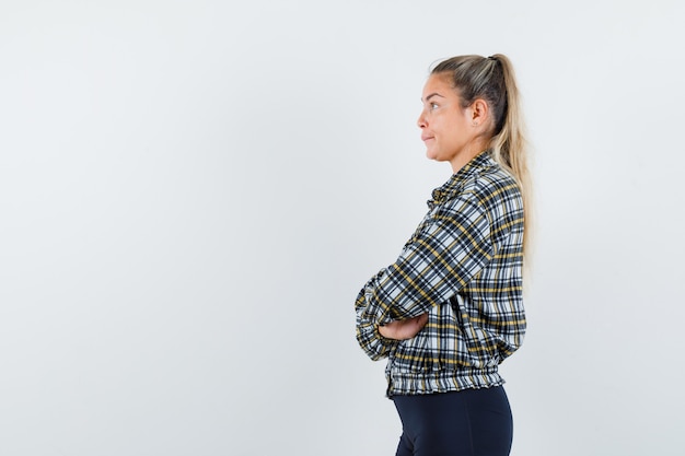 Free Photo young lady standing with crossed arms in checked shirt and looking pensive .