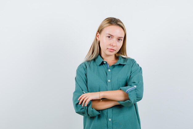 Young lady standing with crossed arms in green shirt and looking confident.