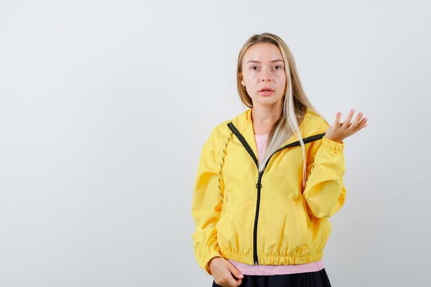 Young lady stretching hand in questioning gesture in t-shirt, jacket and looking confident