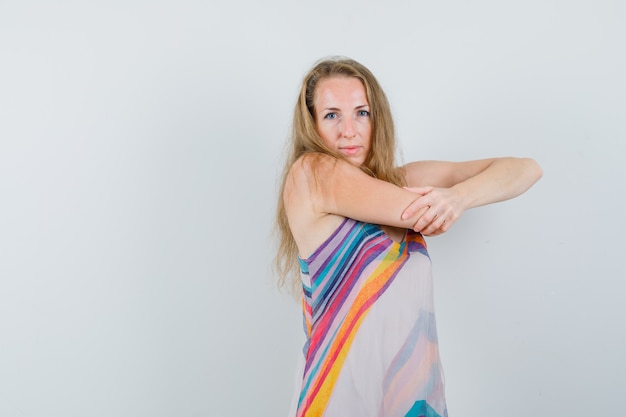 Young lady stretching her arm in summer dress and looking confident 