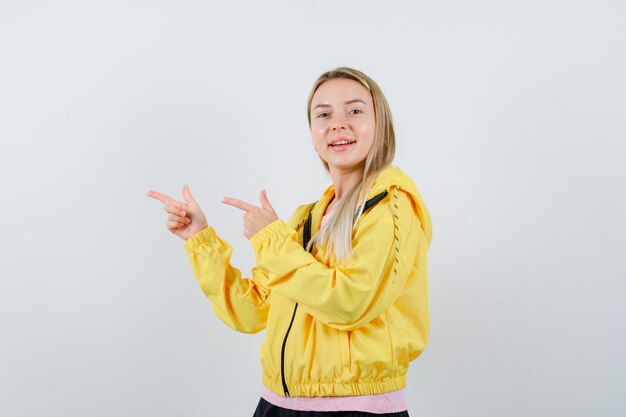 Young lady in t-shirt, jacket pointing to the left side and looking happy