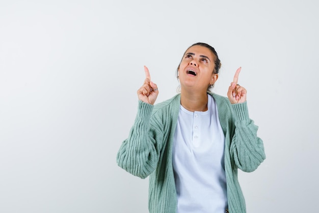 Young lady in t-shirt, jacket pointing up and looking amazed