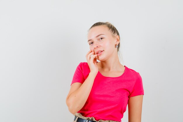 Young lady in t-shirt touching her face skin and looking elegant