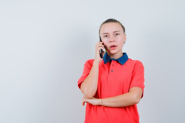 Young lady talking on mobile phone in t-shirt and looking pensive