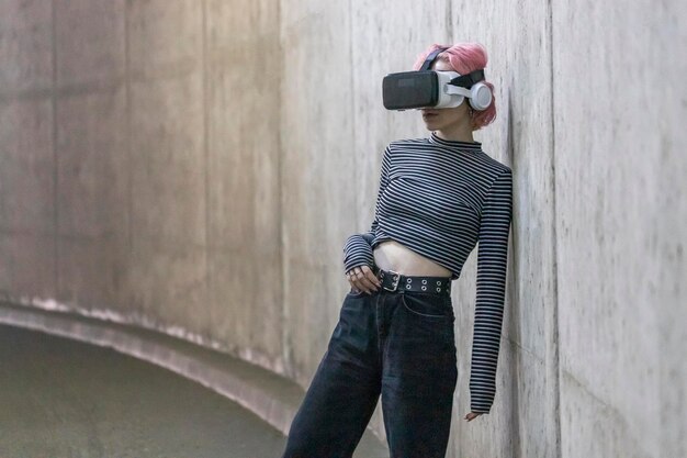 Young lady wears VR set and leaning on wall