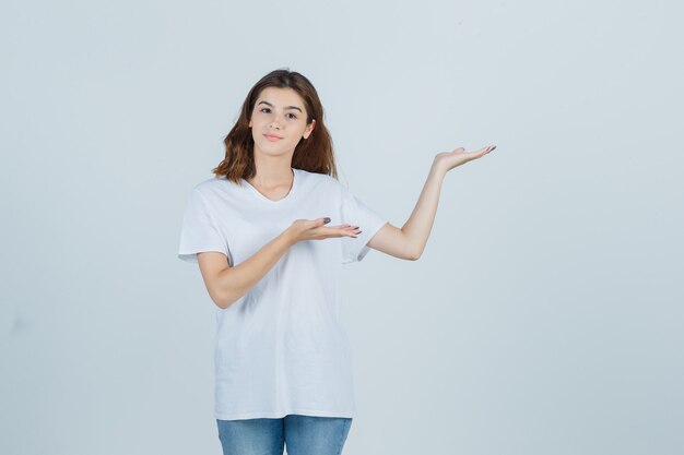 Young lady welcoming in t-shirt, jeans and looking pretty. front view.