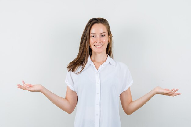 Young lady in white blouse opening arms while smiling and looking pleased