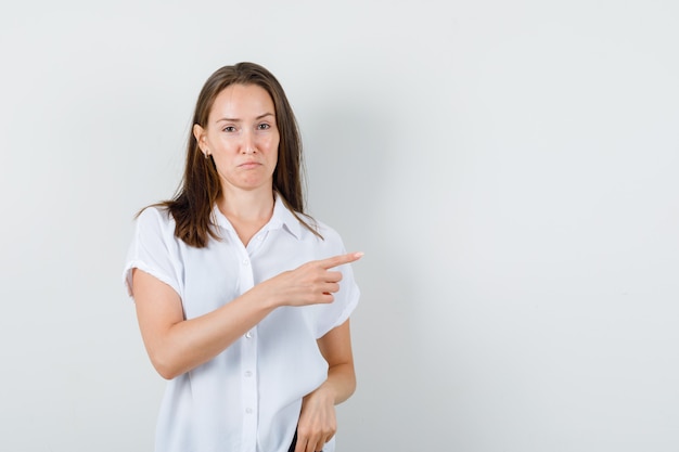 Young lady in white blouse pointing aside