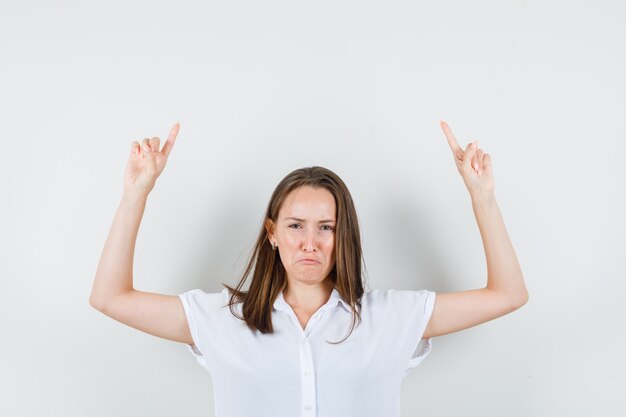 Young lady in white blouse pointing up and looking crazy