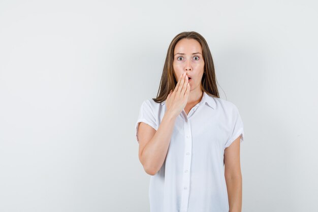 Young lady in white blouse showing what to do gesture and looking helpless