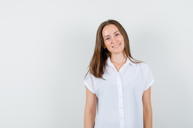 Young lady in white blouse standing while smiling and looking pretty