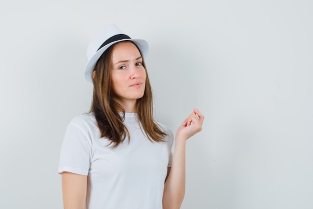 Free photo young lady in white t-shirt hat looking at camera while thinking and looking sensible