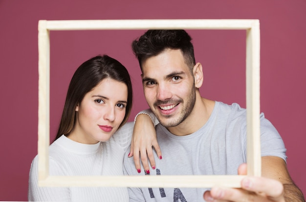 Young lady with hand on shoulder of positive guy showing photo frame