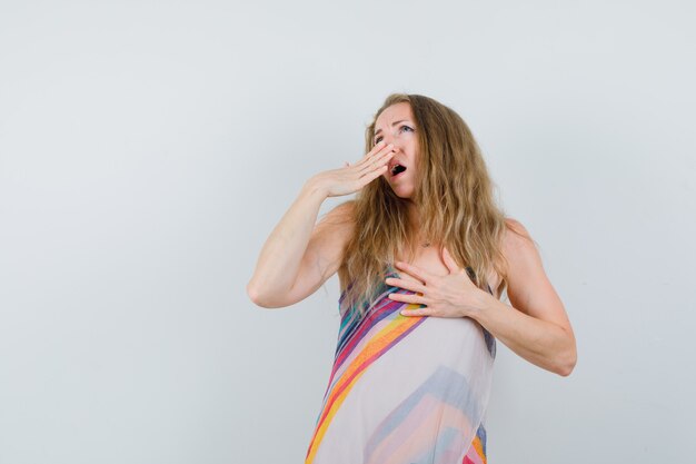 Young lady yawning in summer dress and looking sleepy 