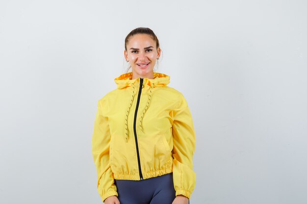 Young lady in yellow jacket posing and looking joyful , front view.