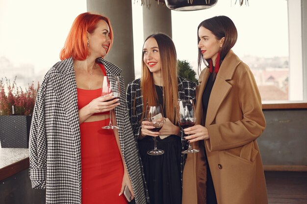 Young laughing friends drinking rose wine from glass outside.