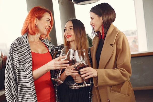 Young laughing friends drinking rose wine from glass outside.