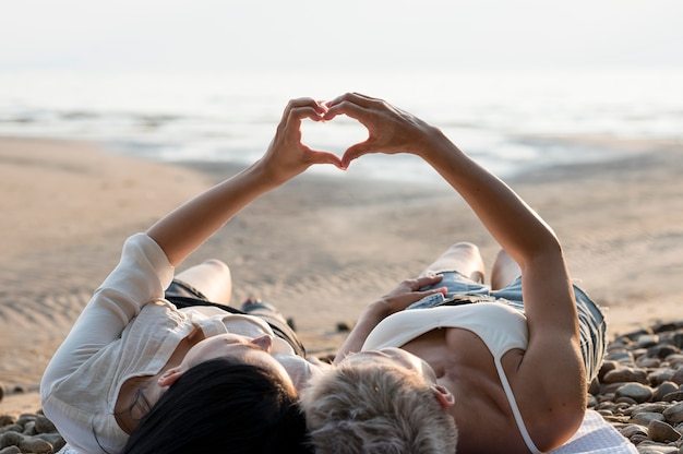 Free photo young lesbian couple forming hand heart shape