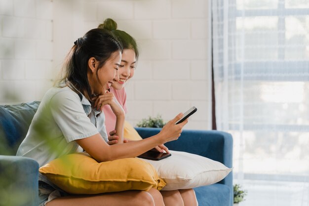 Young Lesbian lgbtq women couple using mobile phone at home