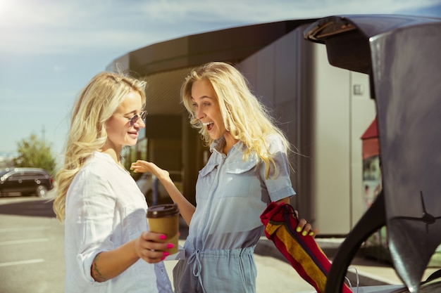 Free photo young lesbian's couple preparing for vacation trip on the car in sunny day. shopping and drinking coffee before going to sea or ocean. concept of relationship, love, summer, weekend, honeymoon.