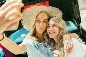 Free photo young lesbian's couple preparing for vacation trip on the car in sunny day