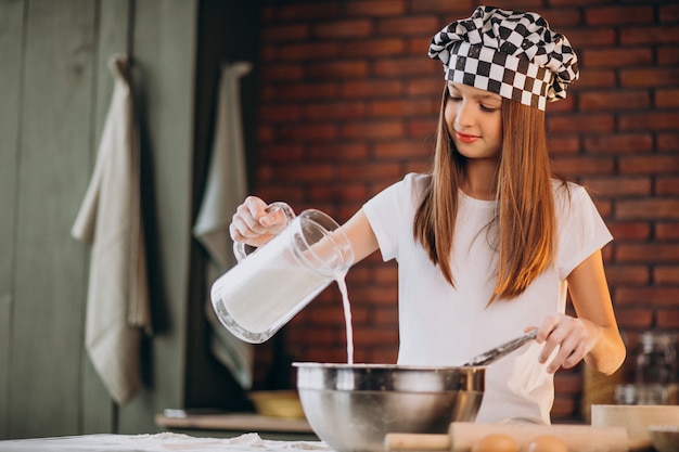 Free photo young little girl baking pastry at the kitchen for breakfast