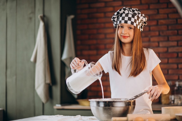 Free photo young little girl baking pastry at the kitchen for breakfast