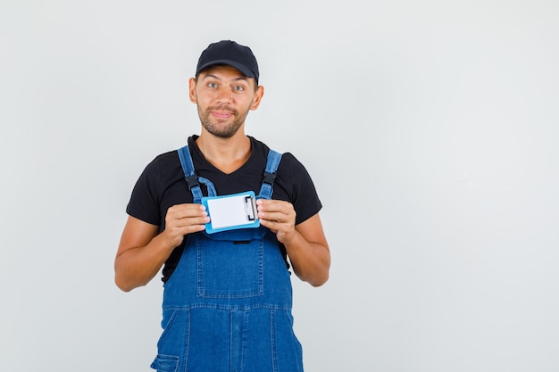 Free Photo young loader in uniform holding mini clipboard and smiling , front view.