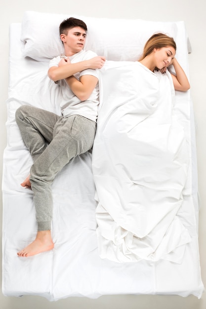 The young lovely couple lying in a white bed, love lconcept, top view