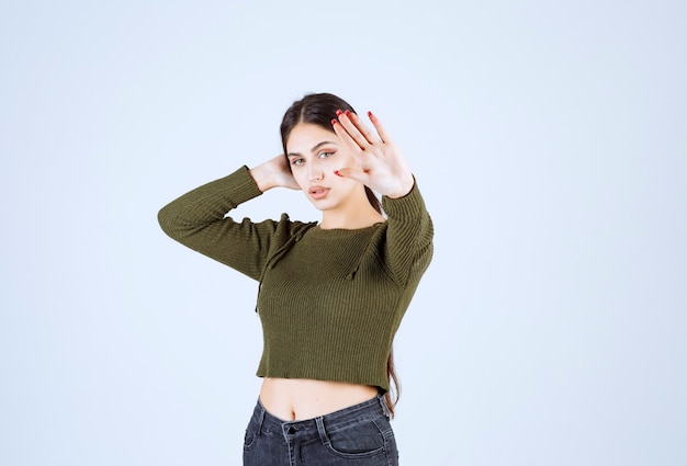 A young lovely woman model posing to camera and giving stop sign