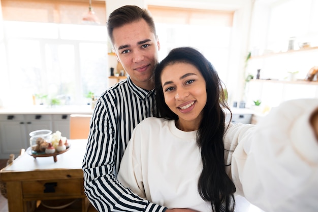 Free photo young lovers hugging and taking selfie in kitchen