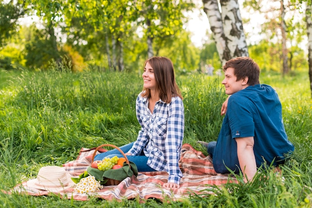 Free photo young lovers sitting on blanket in birch forest