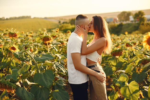 Young loving couple is kissing in a sunflower field. Portrait of couple posing in summer in field.