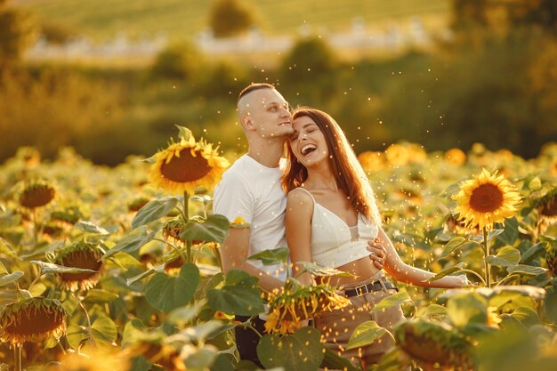 Young loving couple is kissing in a sunflower field. Portrait of couple posing in summer in field.