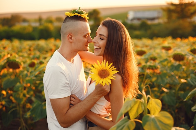 Young loving couple is kissing in a sunflower field. Portrait of couple posing in summer in field.