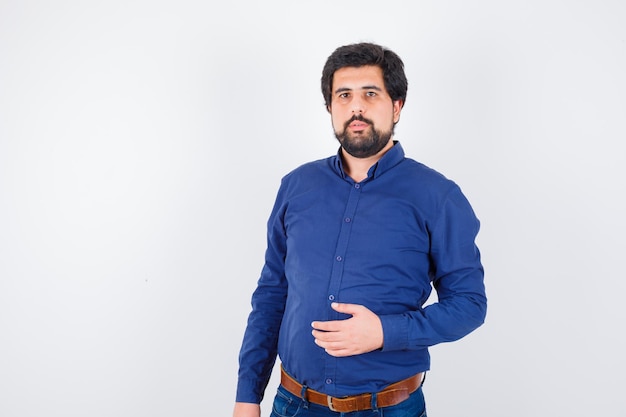 Free photo young male in blue shirt posing while standing and looking sensible , front view.