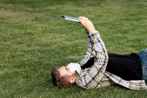 Young male browsing tablet outdoors