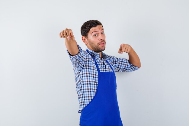 Young male cook in a blue apron and a shirt