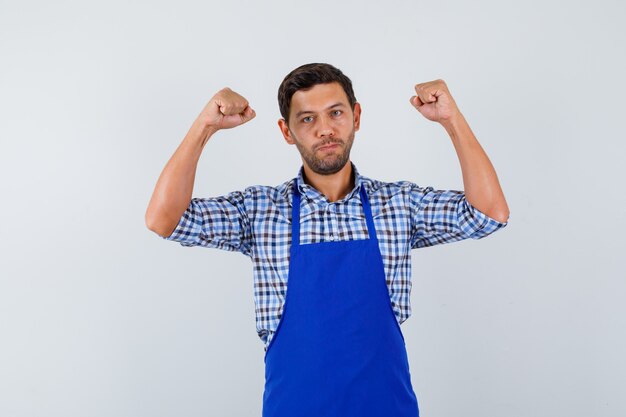 Young male cook in a blue apron and a shirt