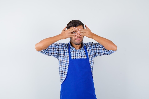 Young male cook in a blue apron and a shirt