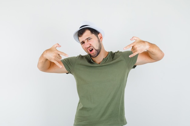 Young male doing rock symbol in green t-shirt and hat and looking cool