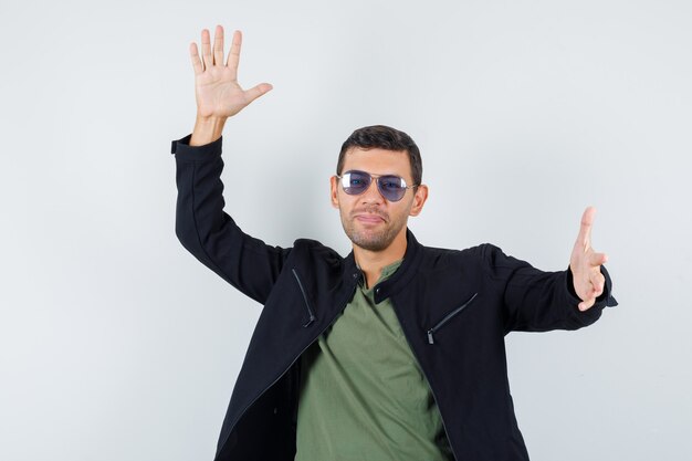 Young male gesturing with hands in t-shirt, jacket and looking happy. front view.