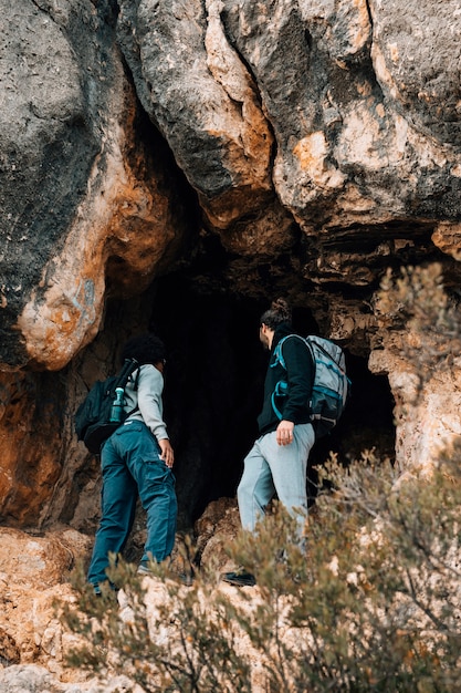 Free Photo young male hiker with their backpack standing in front of rocky cave