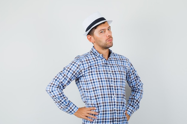 Young male holding hands on waist in checked shirt